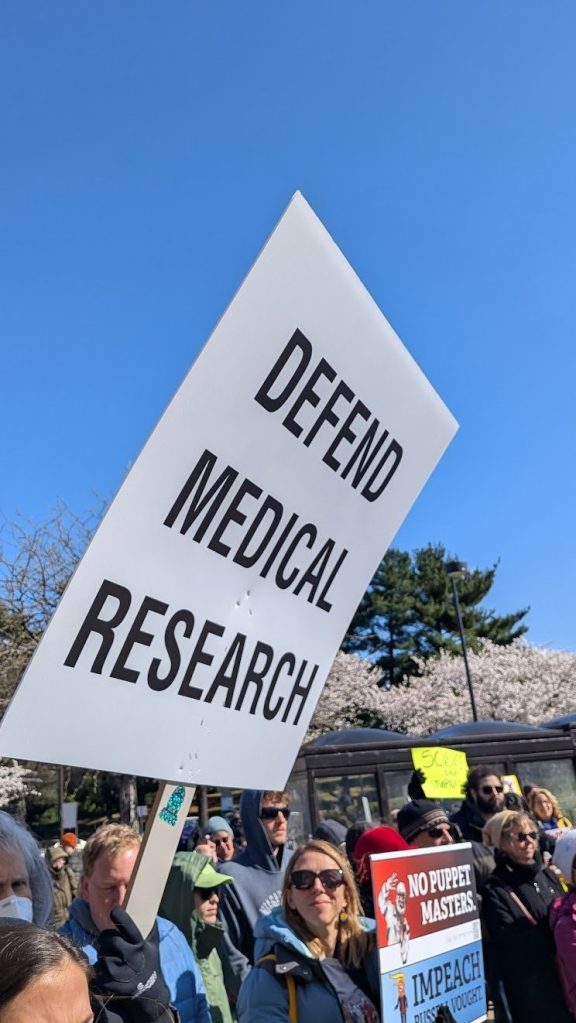 A white sign with black letters reads "Defend medical research"